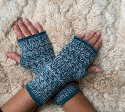 Teal & White Nordic Alpaca Fingerless Gloves worn on hands resting on a sheepskin rug