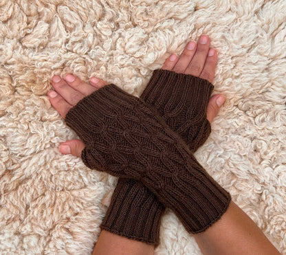 Chocolate Brown Cable Knit Alpaca Fingerless Gloves worn on hands resting on a sheepskin rug