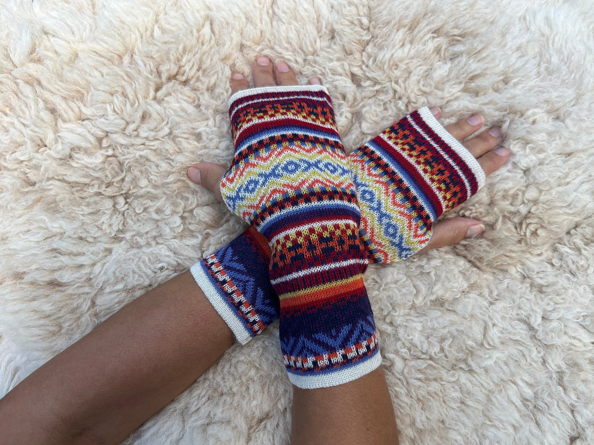 Navy & Mustard Fair Isle Baby Alpaca Fingerless Gloves worn on hands resting on a sheepskin rug