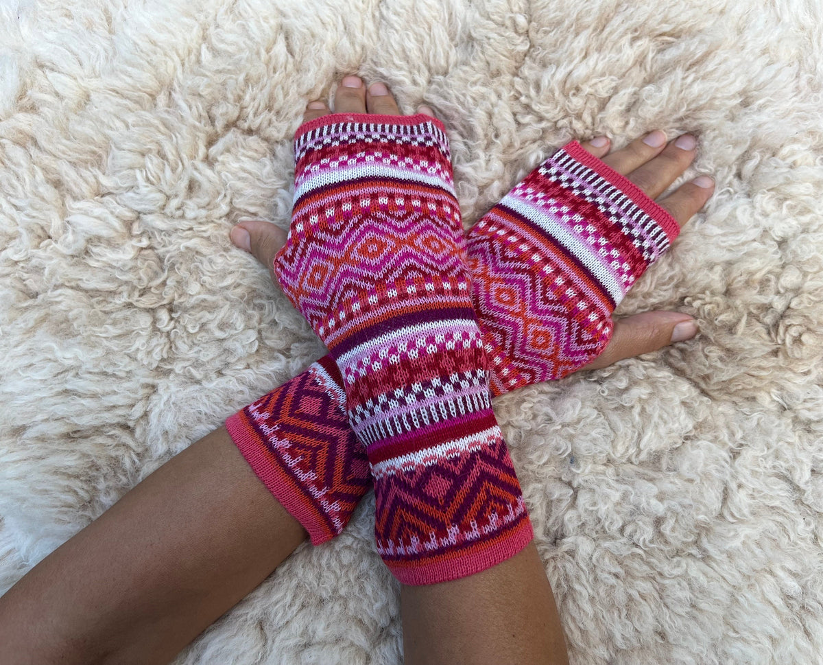 Fair Isle Baby Alpaca Fingerless Gloves worn on hands resting on a sheepskin rug
