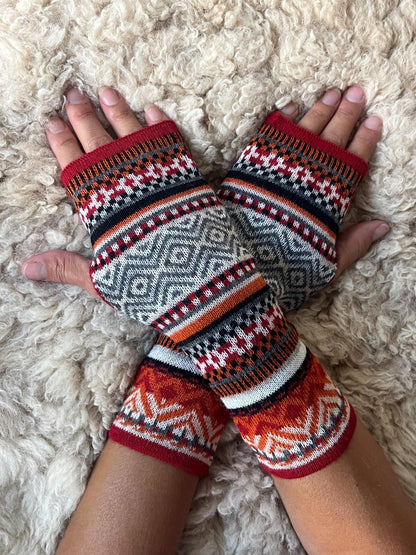 Fair Isle Baby Alpaca Fingerless Gloves worn on hands resting on a sheepskin rug