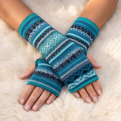 Aqua & Teal Fair Isle Baby Alpaca Fingerless Gloves worn on hands resting on a sheepskin rug