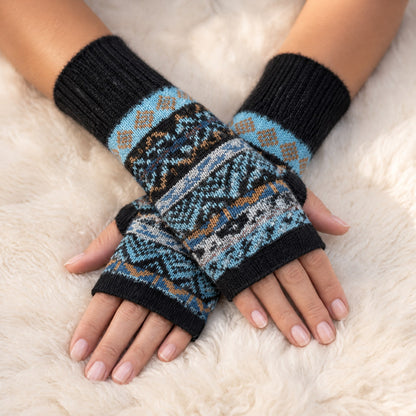 Black & Blue Fair Isle Alpaca Fingerless Gloves worn on hands resting on a sheepskin rug