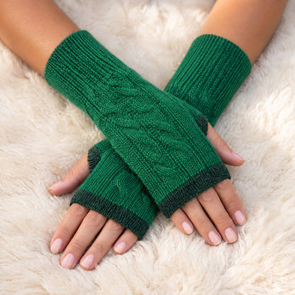 Emerald Green Reversible Cable Knit Baby Alpaca Fingerless Gloves worn on hands resting on a sheepskin rug