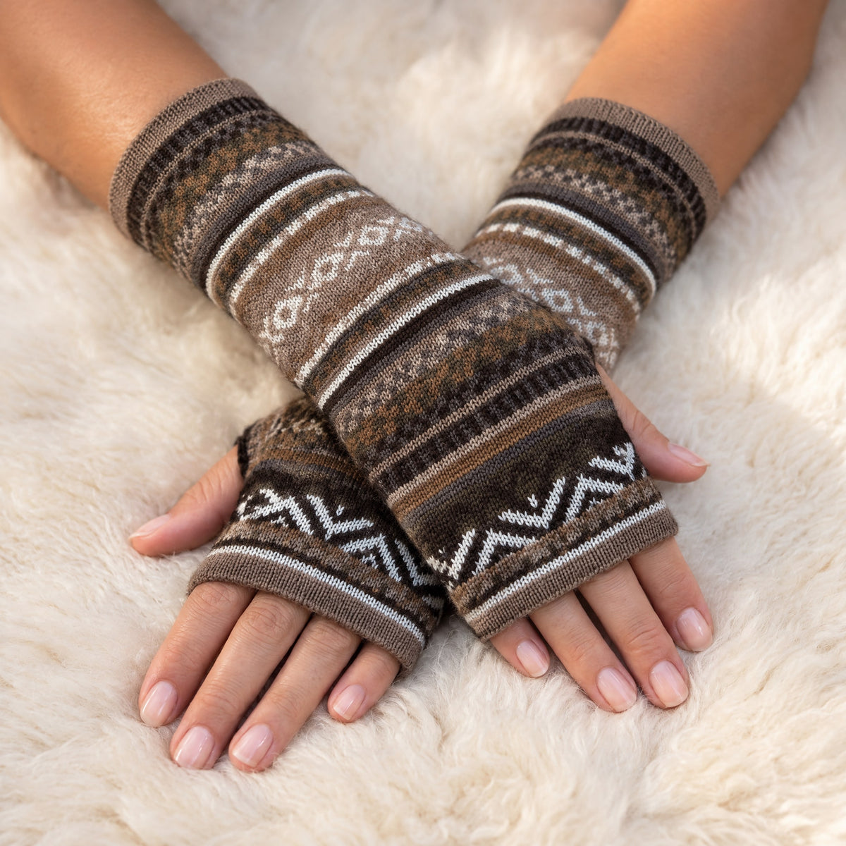 Mocha Brown Fair Isle Baby Alpaca Fingerless Gloves worn on hands resting on a sheepskin rug