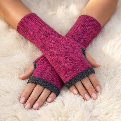 Pink & Grey Reversible Cable Knit Baby Alpaca Fingerless Gloves worn on hands resting on a sheepskin rug