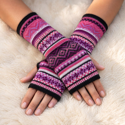 Pink & Plum Fair Isle Baby Alpaca Fingerless Gloves worn on hands resting on a sheepskin rug
