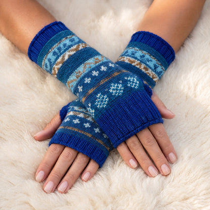 Royal Blue Fair Isle Alpaca Fingerless Gloves worn on hands resting on a sheepskin rug