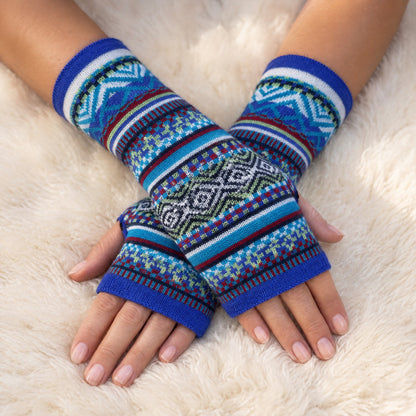 Royal Blue & Turquoise Fair Isle Baby Alpaca Fingerless Gloves worn on hands resting on a sheepskin rug