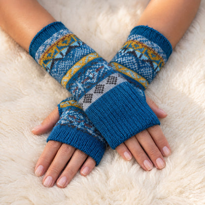 Teal Blue Fair Isle Alpaca Fingerless Gloves worn on hands resting on a sheepskin rug